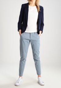 Námořnický blazer, bílý tričko, světlé modré chinos kalhoty a bílé tenisky. Neformální outfit s přizpůsobeným střihem a čist�ými liniemi.