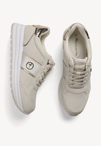 Baskets compensées beiges en matière synthétique texturée, avec un accent métallique brillant et un design classique à lacets.