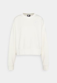 Krämfärgad kort sweatshirt med rund hals, långa ärmar och en liten vit Nike-swoosh-logotyp på vänster bröst. Mjuk tygtextur.