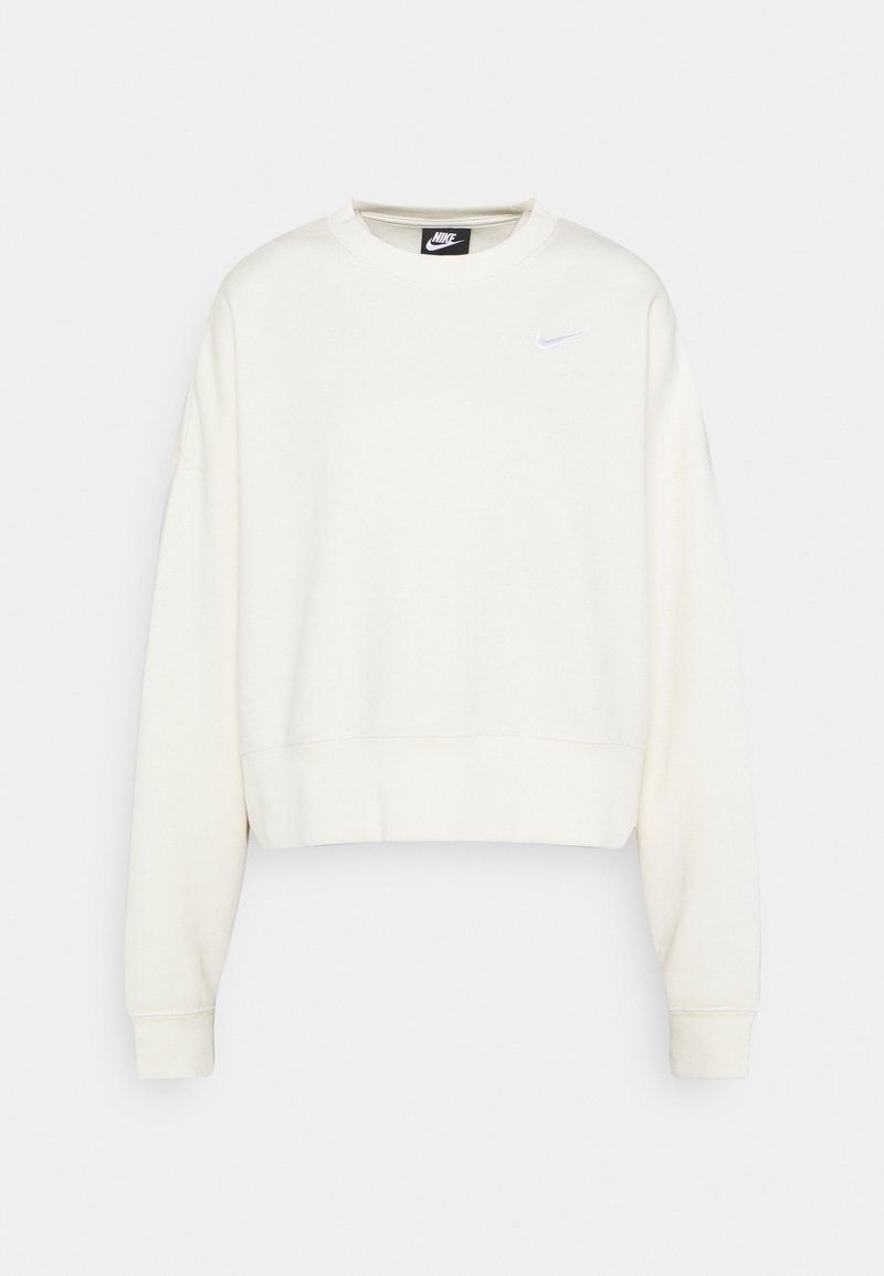 Krämfärgad kort sweatshirt med rund hals, långa ärmar och en liten vit Nike-swoosh-logotyp på vänster bröst. Mjuk tygtextur.