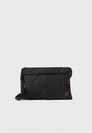 Must tükk-kotitäitjaga musta kootud messenger-kott, mis on varustatud klapiga, kahe esipainiga ja külje rihmaga. Omab tekstureeritud pinda ja väikest logo silti.