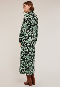 Rochie lungă neagră cu flori, având flori verzi, guler cu nasturi și mâneci lungi, asortată cu bocanci cu toc maro.