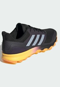 Zapatilla de running negra con parte superior de malla, acentos de ante, tres rayas reflectantes, una entresuela amarillo-naranja y una suela exterior de goma texturizada.