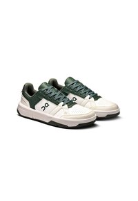 Sneakers featuring a white leather base, green accents, textured overlays, and perforations; lace-up design with a cushioned collar.