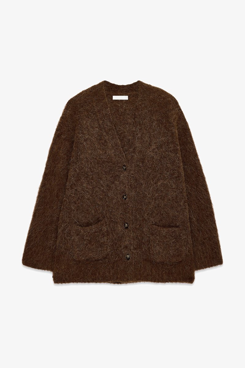 Rudas kardiganas, pagamintas iš purios, tekstūruotos medžiagos. Turi V formos iškirpimą, ilgus rankovės, penkis juodus mygtukus ir dvi priekines kišenes.