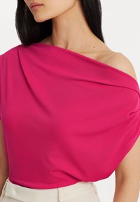Fuchsia off-shoulder topp i mjukt, slätt tyg, med draperad design och subtil textur, parat med ljusfärgad midjeband.