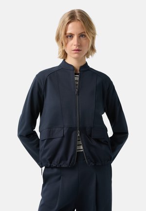Marine blauwe zip-up jas met een staande kraag, voorzien van twee voorzakken en een geplooide zoom, gemaakt van zachte, rekbare stof.