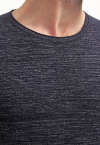 Mörkgrå kortärmad skjorta med en ribbad rund halsringning, med en texturerad tyg som har ett subtilt heatherat mönster.