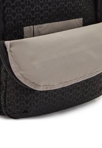 Black patterned backpack material with a dark geometric design. Features a cream flap closure and zipper for secure storage.