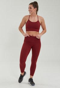 Bordeaux sportbh en legging set, gemaakt van zachte, rekbare stof. Kenmerkt een nauwsluitend ontwerp, verstelbare banden en naadloze taille.