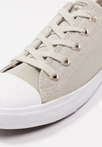 Baskets en toile grise avec embout en caoutchouc blanc, œillets métalliques et lacets plats. Tige texturée avec de fines rayures verticales.