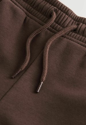 Brune bomuldssweatpants med en glat tekstur, der har en ribbet talje og matchende snore til justerbar pasform.
