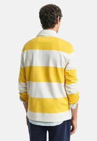 Geel en wit gestreepte lange mouwen blouse met een kraag, ontspannen pasvorm en opgerolde mouwen, gemaakt van zachte katoenen stof.