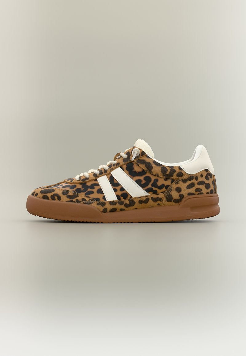 Baskets basses avec imprimé léopard marron et noir, talon et bandes blanches, lacets blancs et semelle en caoutchouc marron.