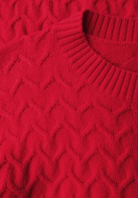 Roter gestrickter Pullover mit einem strukturierten Zickzackmuster und ribbeltem Kragen. Das Material wirkt weich und dick, geeignet für Wärme.