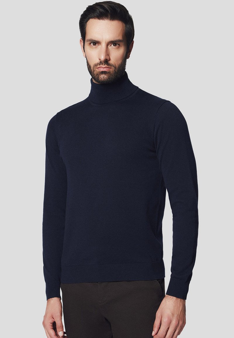 Granatowy sweter typu golf w dopasowanym kroju, wykonany z miękkiego materiału, z prążkowanymi mankietami i dołem dla dodatkowej faktury i detali.