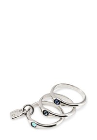 Trois anneaux argentés entrelacés, chacun orné d'une petite pierre précieuse colorée : bleu clair, bleu foncé et bleu marine, avec une finition lisse.