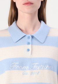 Light blue and cream striped knit polo shirt with a collared neckline, featuring three blue buttons and embroidered text: "From Future Est. 2018."