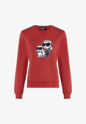 Sweatshirt vermelho com mangas longas, apresentando uma estampa gráfica de um personagem e um gato de óculos de sol. O material parece suave e texturizado.