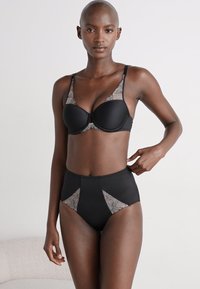 Conjunto de lingerie preto composto por um soutien almofadado com detalhes em renda e cuecas altas com painéis de renda e sólidos, textura suave.