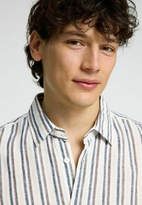 Camicia con collo a righe verticali di colore bianco, blu e marrone. Tessuto leggero, chiusura con bottoni e dettagli di cucitura visibili.