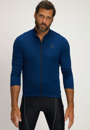 Blaue Langarm-Radsporttrikot mit Reißverschluss vorne, strukturiertem Stoff und einem Logo auf der Brust, kombiniert mit schwarzen Radsportshorts.