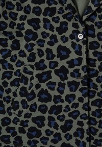 Tissu vert foncé avec motif léopard noir et bleu foncé, bouton unique et poche inclinée avec couture sur le vêtement.