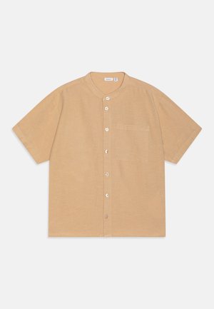 Chemise boutonnière à manches courtes en tissu beige clair, avec un col rond, une poche sur le devant et cinq boutons sur le devant. Texture lisse.