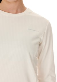 Leichtes, langärmeliges Oberteil in Creme mit einem dezenten Texturmuster. Verfügt über einen runden Ausschnitt und ein kleines "ENDURANCE"-Logo in Silber.