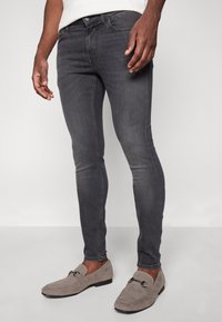 Slim-fit, donkergrijze jeans met een lichte stretch; klassieke vijf-pocket stijl met metalen hardware en subtiele vervaging op de bovenbenen.