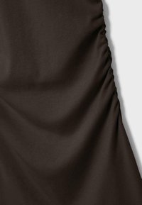 Dunkelbrauner Stoff mit glatter Textur, der an einer Seite gerafft ist und dabei sanfte Falten und einen eleganten Fall erzeugt.