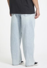 Lys blå, oversized denimjeans med straight-leg design. Har to baklommer og en falmet tekstur. Kombinert med svarte joggesko.