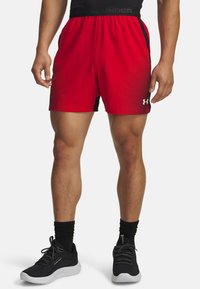Pantalones cortos deportivos rojos con acentos laterales negros, con un patrón de puntos. Hechos de un material ligero, diseñados para la comodidad y la movilidad.