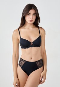 Czarny zestaw bielizny składający się z push-up biustonosza z koronkowymi detalami oraz majtek o wysokim stanie z koronkowymi akcentami. Gładka tekstura materiału.
