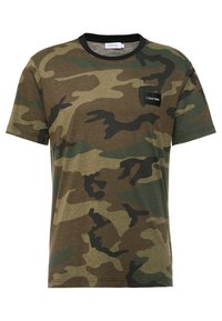 Camiseta de camuflaje hecha de algodón, con tonos de verde y marrón, mangas cortas y un cuello redondo negro con un pequeño parche de logo.