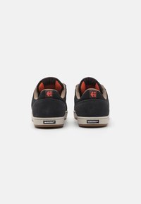 Juodos suede sportbačiai su rudais akcentais, turintys tekstūruotą kulną, tinklelio pamušalą ir Michelin logotipą ant smėlio spalvos gumos pado.