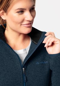 Navy-Fleecejacke mit Reißverschluss und hohem Kragen, strukturierter Oberfläche und kontrastierendem schwarzen Innenfutter. Mit Logo und glattem Reißverschluss-Zipper.
