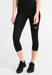 Leggings capri neri realizzati in tessuto elasticizzato, con il logo Nike bianco sul lato sinistro, caratterizzati da una texture liscia e un design aderente.