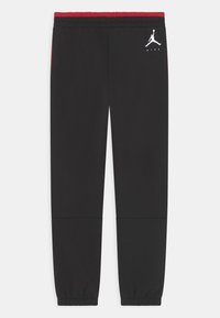 Schwarze Sportpants mit einem roten elastischen Bund, elastischen Bündchen und einem weißen Air Jordan-Logo am linken Oberschenkel. Glatte Textur.