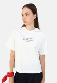 Hvid bomulds t-shirt med korte ærmer og rund halsudskæring. Har rød og marineblå tekst: "GØR TINGEN ENKLE" Tag dig tid, NYD LIVET."