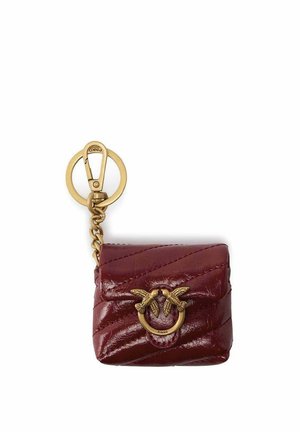 Pequeña bolsa de cuero rojo oscuro acolchada con anillo dorado y dos cierres en forma de pájaro, unida a un llavero dorado con clip.