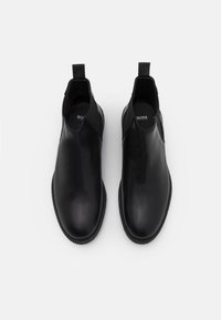 Bottes Chelsea en cuir noir avec panneaux latéraux élastiques, bout arrondi et semelle en caoutchouc. Design minimaliste avec logo BOSS sur la semelle intérieure.