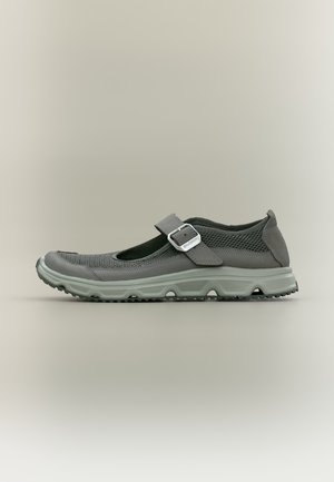 Chaussure style Mary Jane grise avec tige en mesh, bride réglable à boucle et semelle épaisse texturée pour une utilisation extérieure ou décontractée.