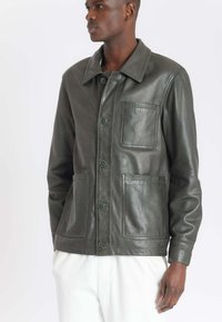 Groene leren jas met een kraag, voor knopen, twee zijzakken en een borstzak. Soepele textuur met een getailleerde pasvorm.