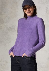 Lila gestrickter Pullover mit hohem Kragen, gerippten Bündchen und Saum. Getragen über dunklen Jeans. Strukturiertes Gewebe mit weichem Finish.