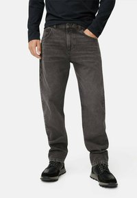 Gray denim jeans with a relaxed fit, five pockets, and a button closure. Worn with black lace-up boots. Fabric has a slight texture.
