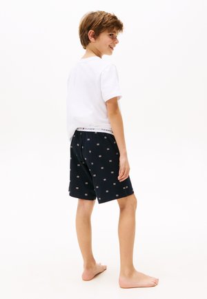 Boys' outfit featuring a white T-shirt and navy shorts with a small geometric pattern. The shorts have an elastic waistband with logo detail.