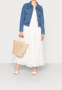 Jeansjacka, vit spets maxi klänning, vävd beige toteväska och vita klackar med öppen tå. Funktioner inkluderar knappstängningar och spetsmönster.