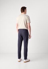 Beige kortärmad skjorta i slim fit, matchad med marinblå byxor med bakfickor, kompletterad med vita sneakers med bruna sulor.