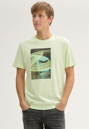 Lichtgroen T-shirt met korte mouwen en een grafische print van abstracte vormen en tekst. Gemaakt van zachte stof, met een relaxte pasvorm en een ronde hals.